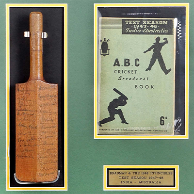 A FRAMED AND SIGNED MINI CRICKET BAT FEATURING AUTOGRAPHS FROM BOTH THE AUSTRALIAN AND INDIAN CRICKET TEAMS(1947-48 TEST SEASON)